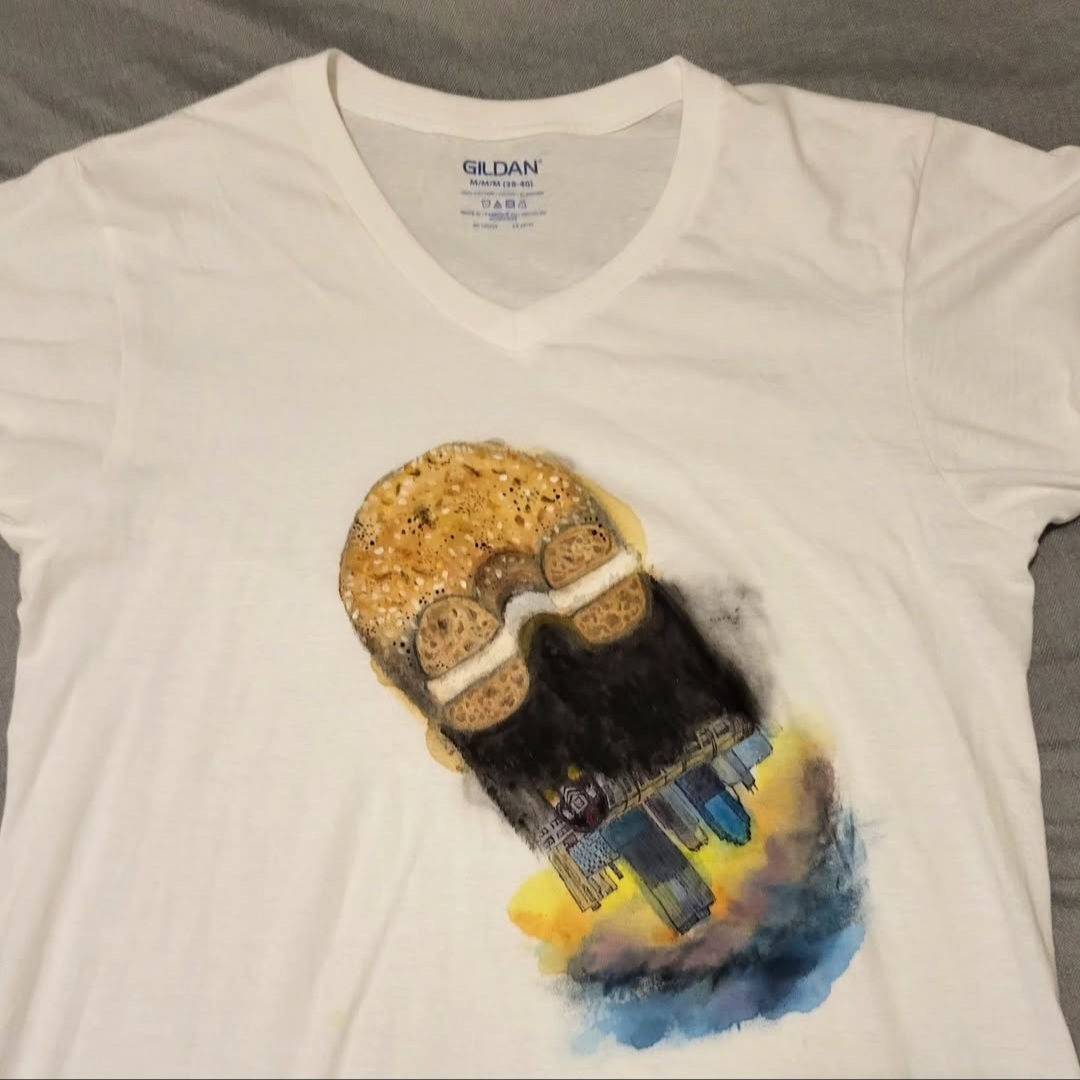 Bagel with city skyline in the shadow painted onto a shirt